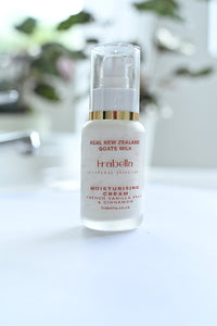 A pump bottle of Frabella brand moisturizing cream with French Pear, Vanilla and Cinnamon scents, positioned on a white surface with a blurred background.